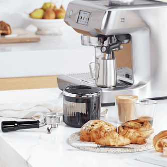 Portafilter, puck sucker, milk jug, latte, croissants.