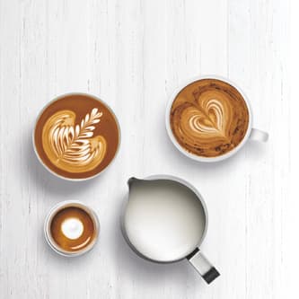 Three espresso drinks with microfoam milk in jug