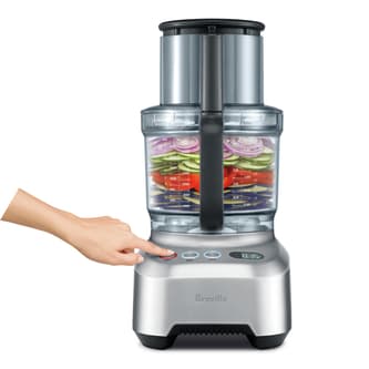 Multiple types of vegetables being sliced in the Breville Sous Chef 16 Pro.