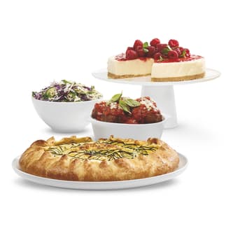 Cheesecake on a cake stand, a green salad in a bowl, meatballs in a bowl, and a savoury tarte tatin