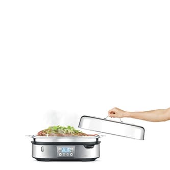 Someone lifting the lid of the Steam Zone and a whole fish being cooked inside.