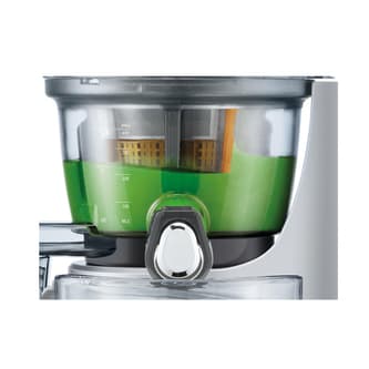 Green juice is being mixed in juicer just before being poured.