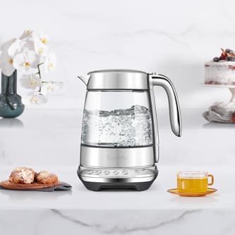 The smart crystal luxe kettle next to a plate of biscuits and cup of tea