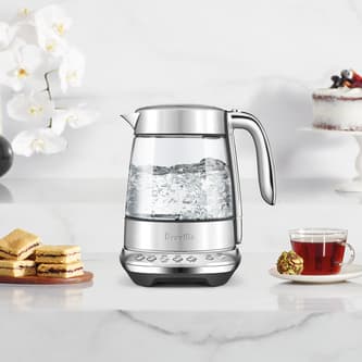 The smart crystal luxe kettle next to a plate of biscuits and cup of tea