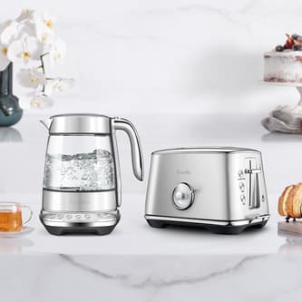 The smart crystal luxe kettle and toaster next to a cup of tea and bread