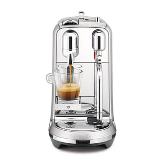 Front view of machine with a cup of espresso, with layer of latte on top.