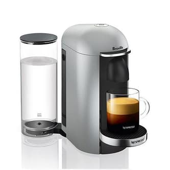 Side view of machine with coffee pod being inserted into machine with cup of coffee.