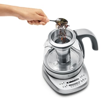 View of kettle and person adding tea to basket.