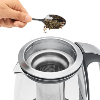 Person adding loose leaf tea to basket.