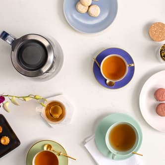 Top view of kettle, tea and biscuits on table.