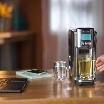 Glass with hot tea under dispenser
