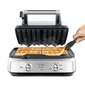 Person removing waffle from waffle maker.