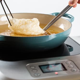 Food is being fried in a pan of oil on top of the precision cooker.