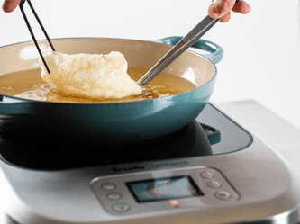 Food is being fried in a pan of oil on top of the precision cooker.