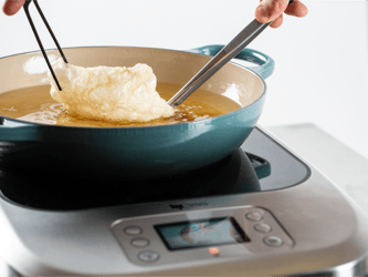 Food is being fried in a pan of oil on top of the precision cooker.