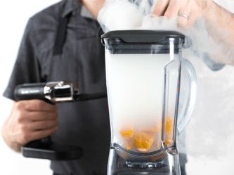 Smoke from the smoking gun fills a glass vessel with food inside.