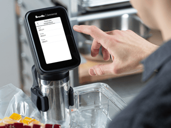 A person touches the screen of the HydroPro™ which is immersed in a container of water.