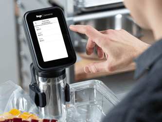 A person touches the screen of the HydroPro™ Plus which is immersed in a container of water.