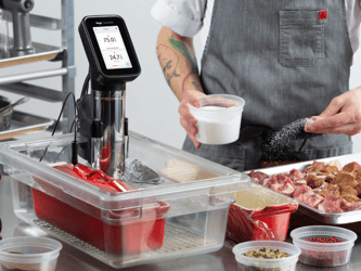 The HydroPro™ Plus is immersed in a body of water while the chef seasons the meat.