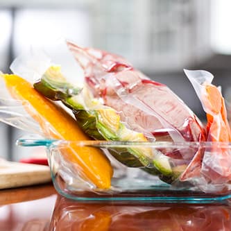 Vacuum sealed meats and vegetables in a glass container.
