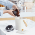Tipping loose coffee pucks into a compost bin.