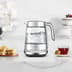 The smart crystal luxe kettle next to a plate of biscuits and cup of tea